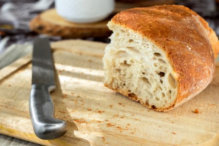 Sliced Bread And Stainless Steel Knife On Top Of Brown Wooden Chopping Board