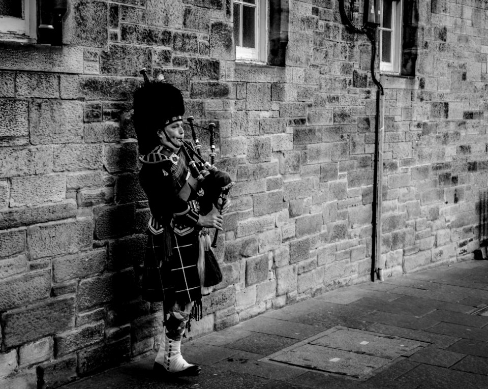 Person Using Bagpipes Near Wall In Grayscale Photography