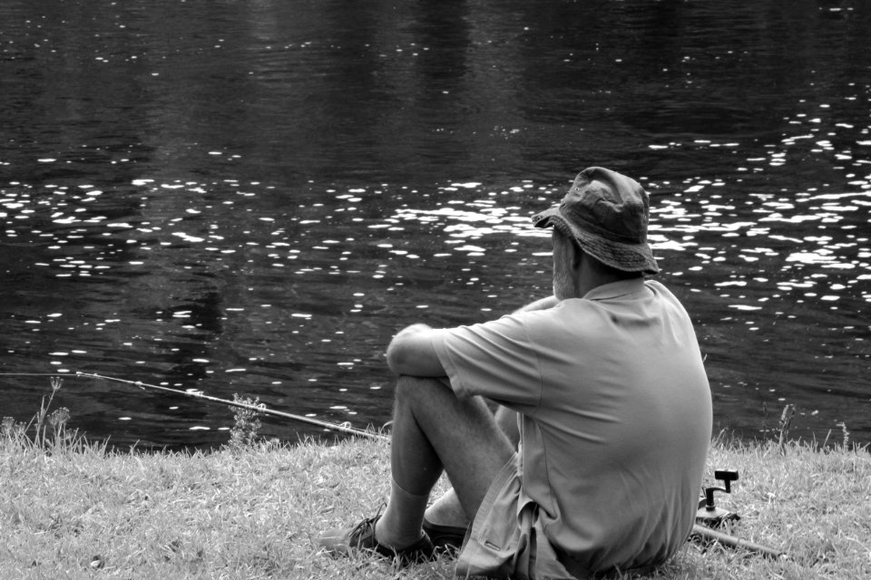 Man Sitting Facing Body Of Water photo