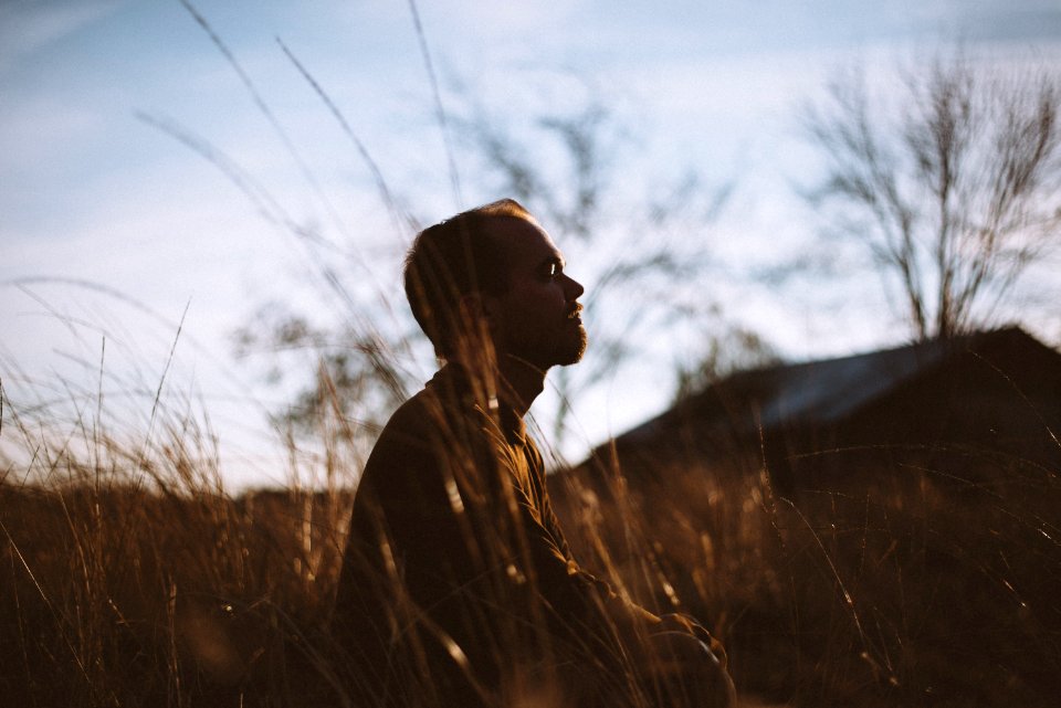 Silhouette Of Man Sitting On Grass Field At Daytime