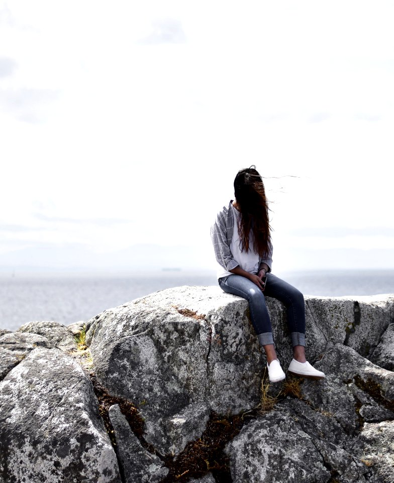 Woman Sits On Gray Rock