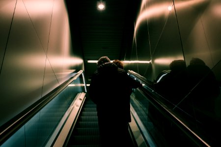 Person In Black Jacket Standing On Escalator photo