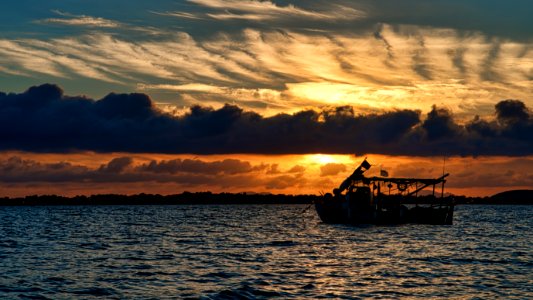 Silhouette Photo Of Boat On Ocean During Golden Hour photo