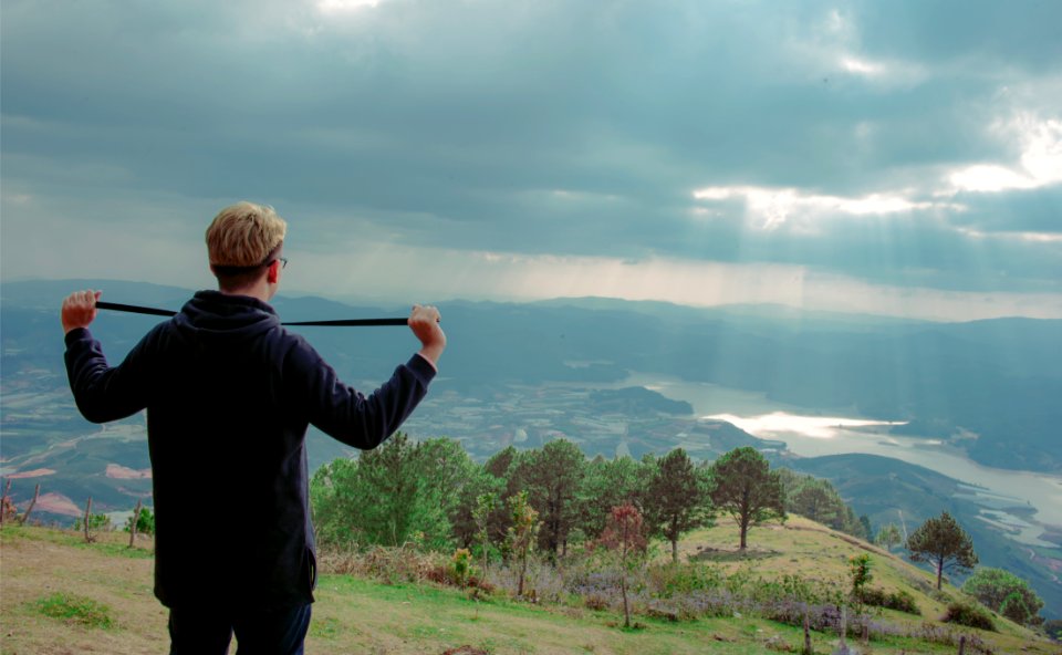 Man Wearing Hoodie Standing On Mountain Under Cloudy Sky photo