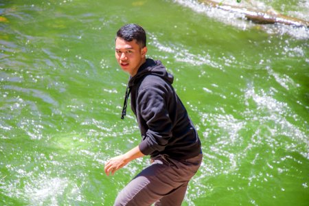 Man In Black Hoodie Standing In Front Of Body Of Water photo