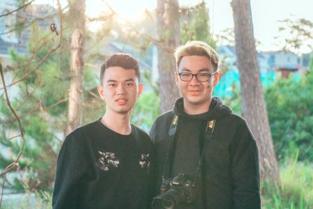 Two Men Standing Near Tree Trunks