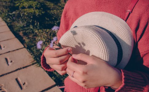 Person Wearing Sweater Holding Flower And Hat photo