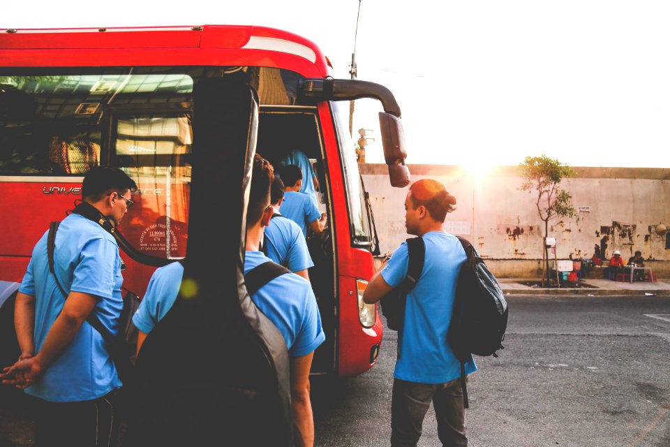 Group Of Men Wearing Blue Shirts About To Enter Red Bus photo