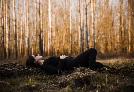 Woman Lying On The Ground Surrounded By Bare Trees