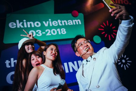 Man In White Suit Jacket Holding Phone In Front Of Three Women photo