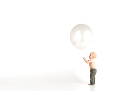 Baby In Black Pants Holding White Balloon While Standing photo