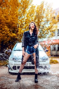 Woman In Black Long-sleeved Top And Blue Denim Shorts Standing In Front Of Car photo