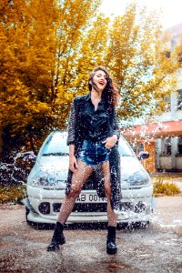 Woman In Black Long-sleeved Top And Blue Denim Shorts Standing In Front Of Car