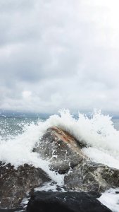 Person Taking Photo Of Sea Waves And Gray Concrete Rock