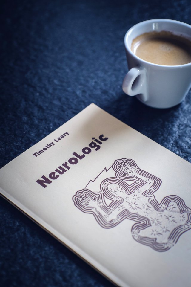 Timothy Learys Neurologic Book Near White Ceramic Cup