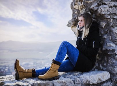 Woman In Black Coat Sitting On Rock