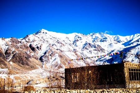 Stone Building At The Base Of Snow-covered Mountain Range Under Clear Bright Blue Sky photo