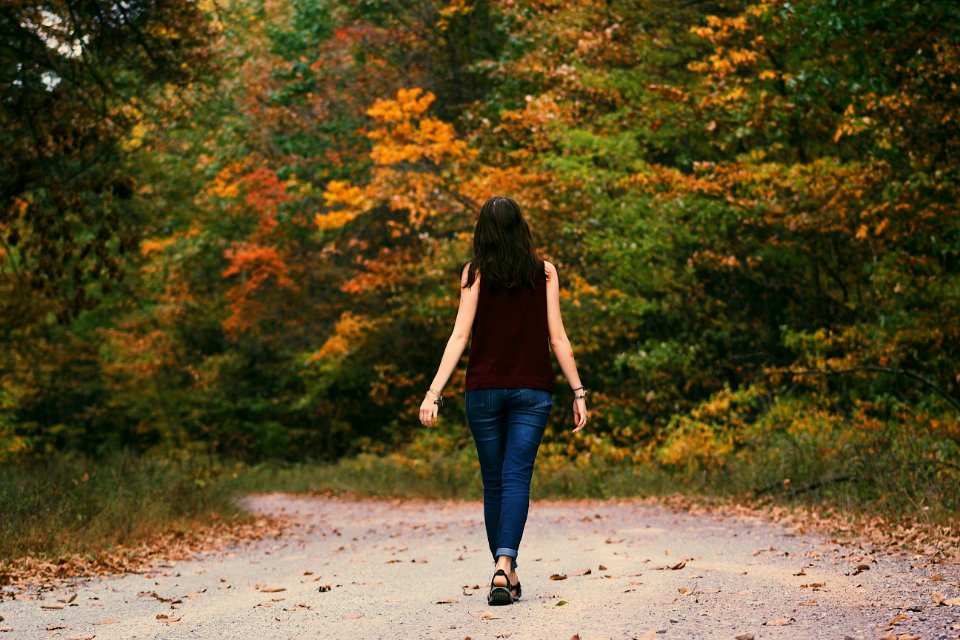 Woman In Brown Sleeveless Dress And Blue Jeans Standing On Gray Path Road