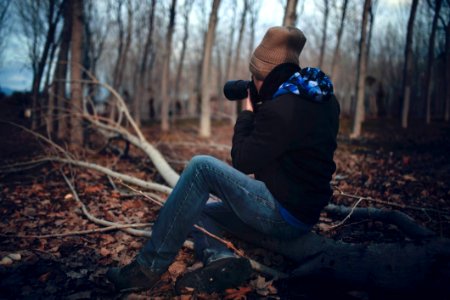 Man Wearing Black Jacket And Blue Jeans Sitting On Tree Branch photo