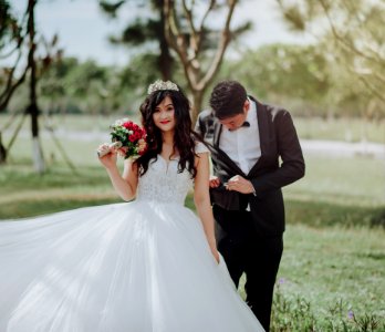 Woman In Wedding Dress Holding Flower With Man In Black Blazer photo