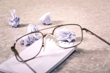 Close-Up Photography Of Eyeglasses Near Crumpled Papers photo