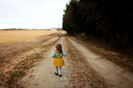 Girl Wearing Blue Long-sleeved Shirt And Yellow Skirt Walking On Pathway photo