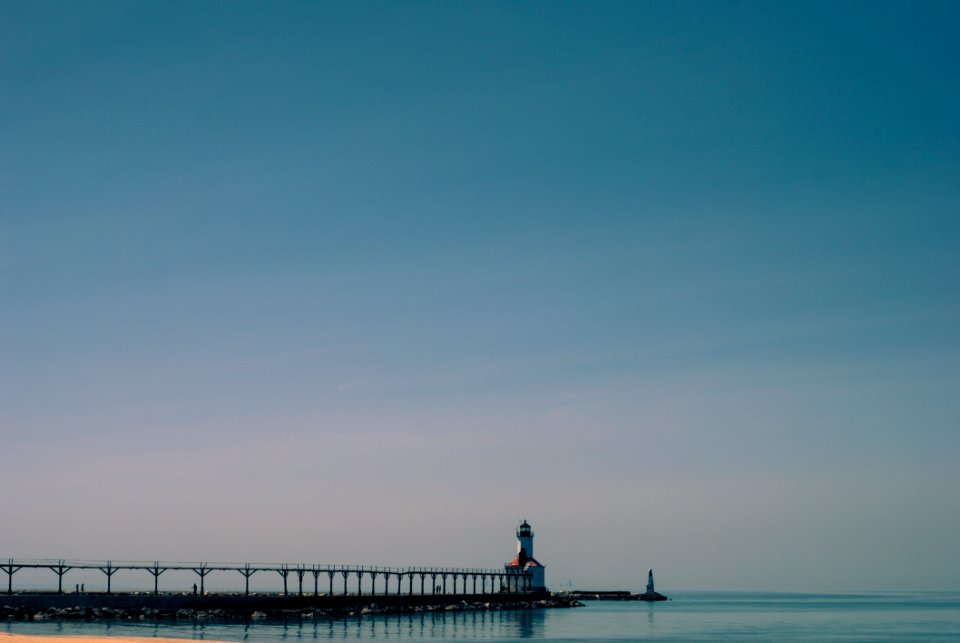 Dock Near White And Brown Concrete Lighthouse Surrounded By Calm Body Of Water