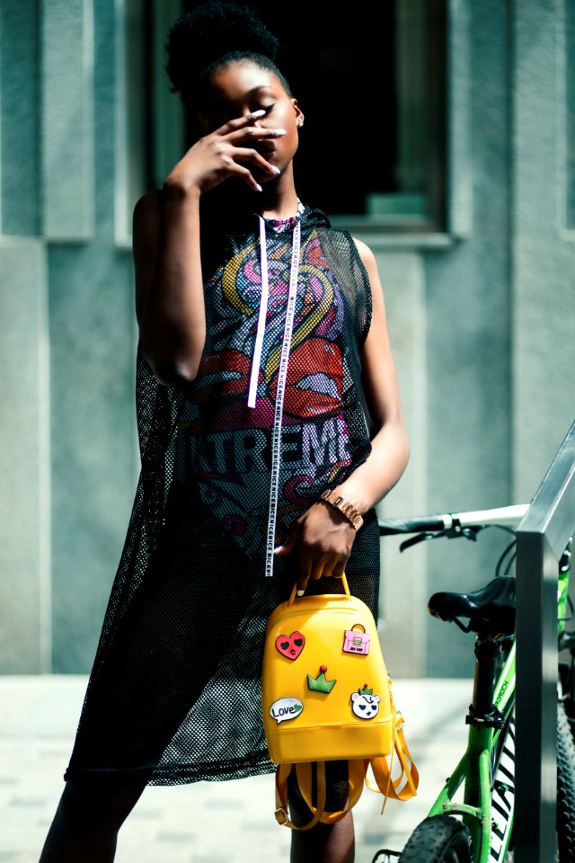 Woman In Black Net Sleeveless Dress Holding Yellow Leather Backpack
