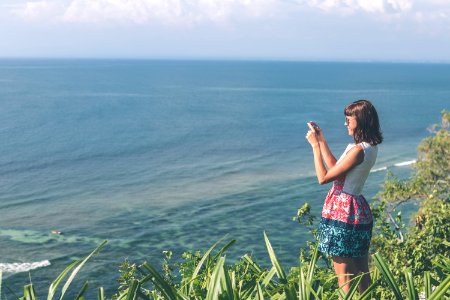 Woman Standing White And Blue Floral Dress Holding Smartphone In Grass Area