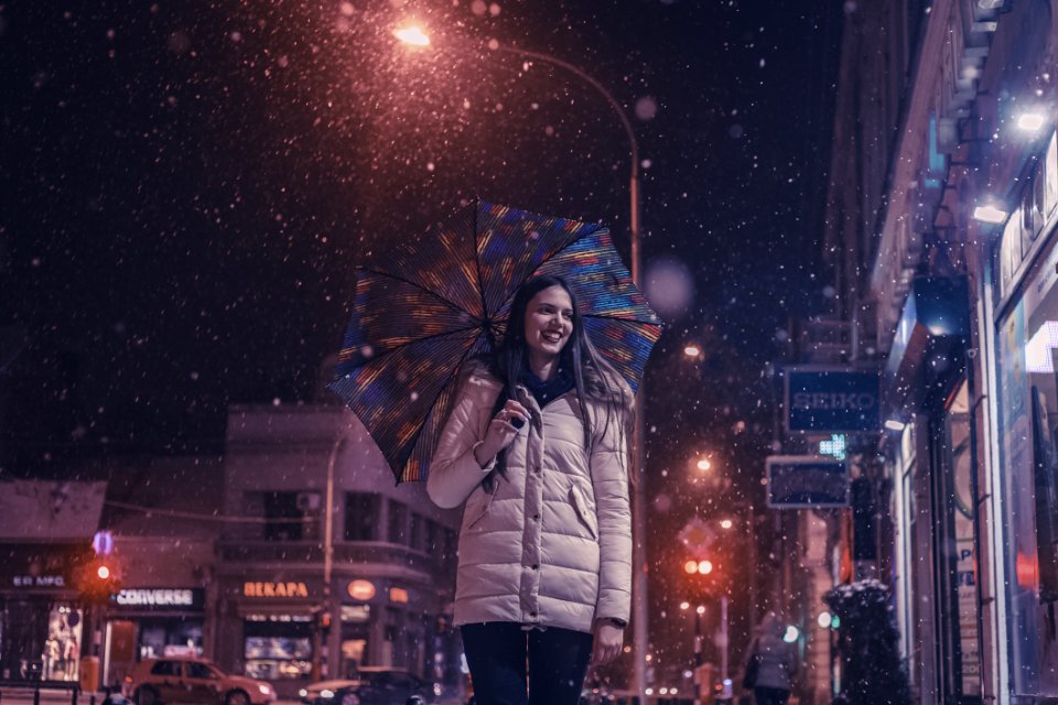 Woman Wearing Brown Bubble Jacket Holding Teal And Yellow Umbrella Near Building