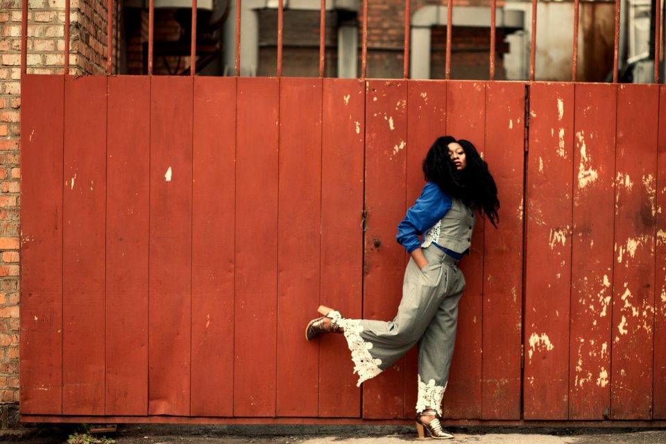 Woman Wearing Grey Jumpsuit Standing Beside Brown Metal Gate photo