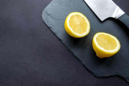 Sliced Lemon Beside Knife On Top Of Black Surface photo