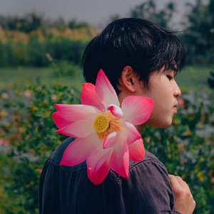 Man Wearing Black Top Holding Pink-and-white Petaled Flower photo