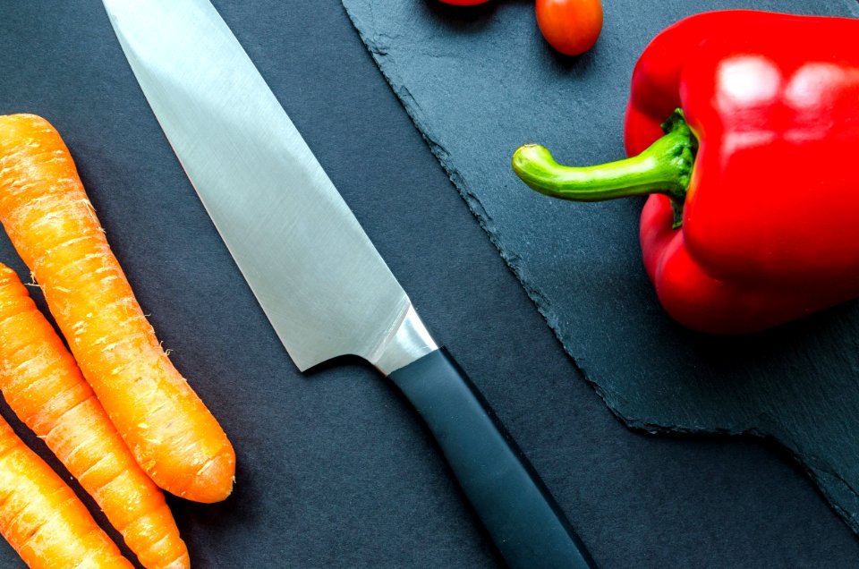 Black Handled Gray Kitchen Knife Beside Orange Carrots And Red Bellpepper