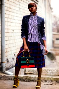 Woman In Blue And White Plaid Cardigan Holding Green And Red Handbag