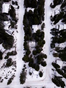 Areal Photography Of Snow Covered Houses Surrounded By Green Trees