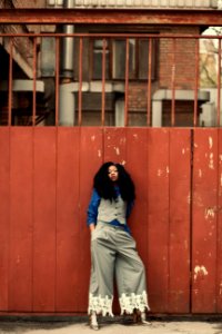 Woman Wearing Blue And Gray Outfit Standing Beside Gate