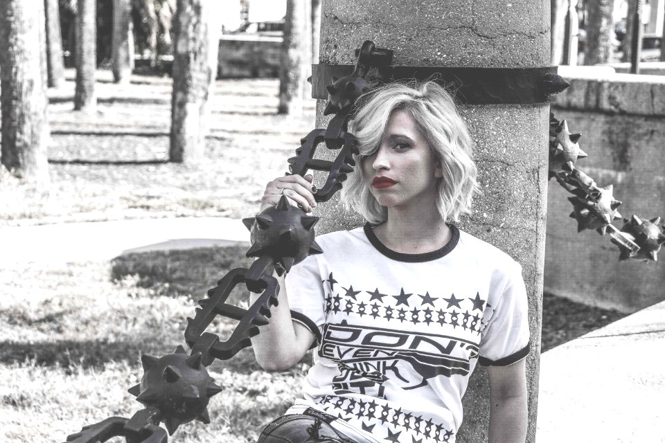 Selective Color Photography Of Woman Laying Her Back At Concrete Column Holding Spike Chain
