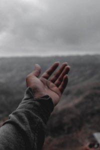 Person Wearing Gray Sleeve Under White Clouds At Daytime