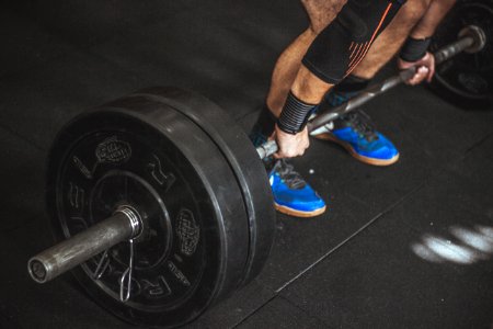 Close-up Of A Persons Lower Body Holding Barbell photo