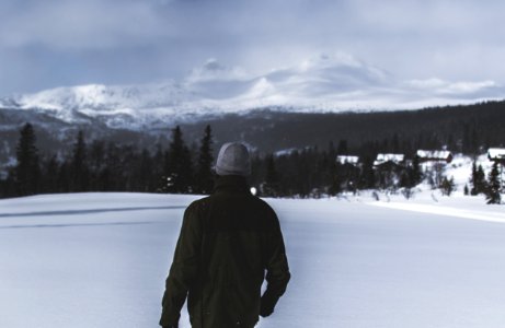 Man Wearing Black Jacket Walking In The Snow photo