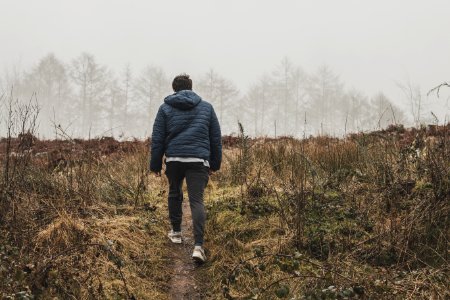 Man Wearing Blue Bubble Hoodie Jacket Walking On Green Grass Field photo