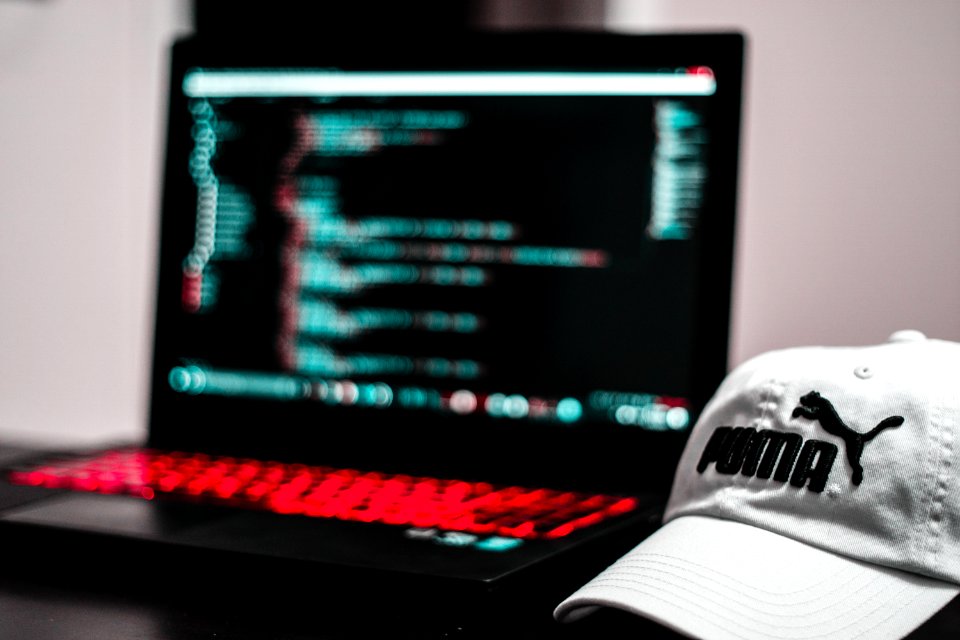 Black And Red Laptop Computer Beside White Puma Curve Brim Cap