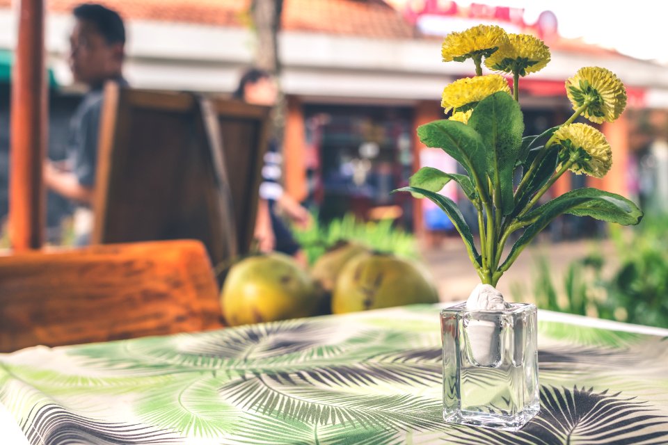 Yellow Flower Arrangement In Vase On Top Of Table
