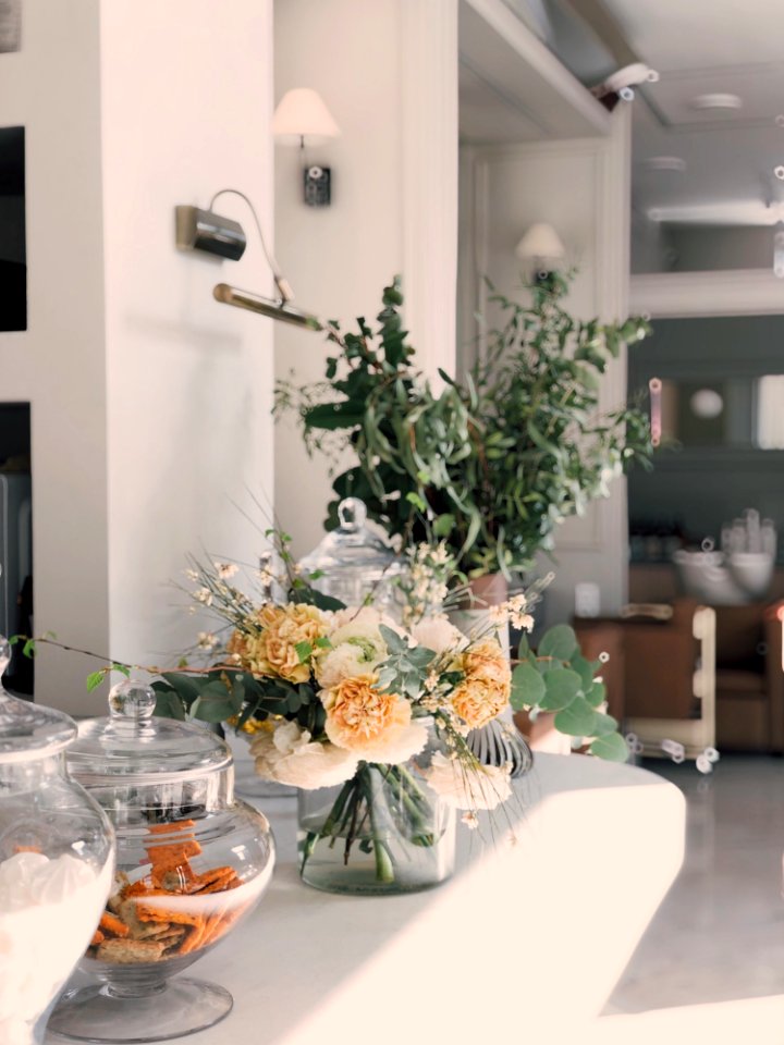 White And Yellow Petaled Flowers Centerpiece Near Clear Glass Jars On Top Of White Wooden Table photo