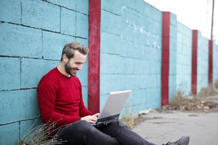 Man Leaning Against Wall Using Laptop photo