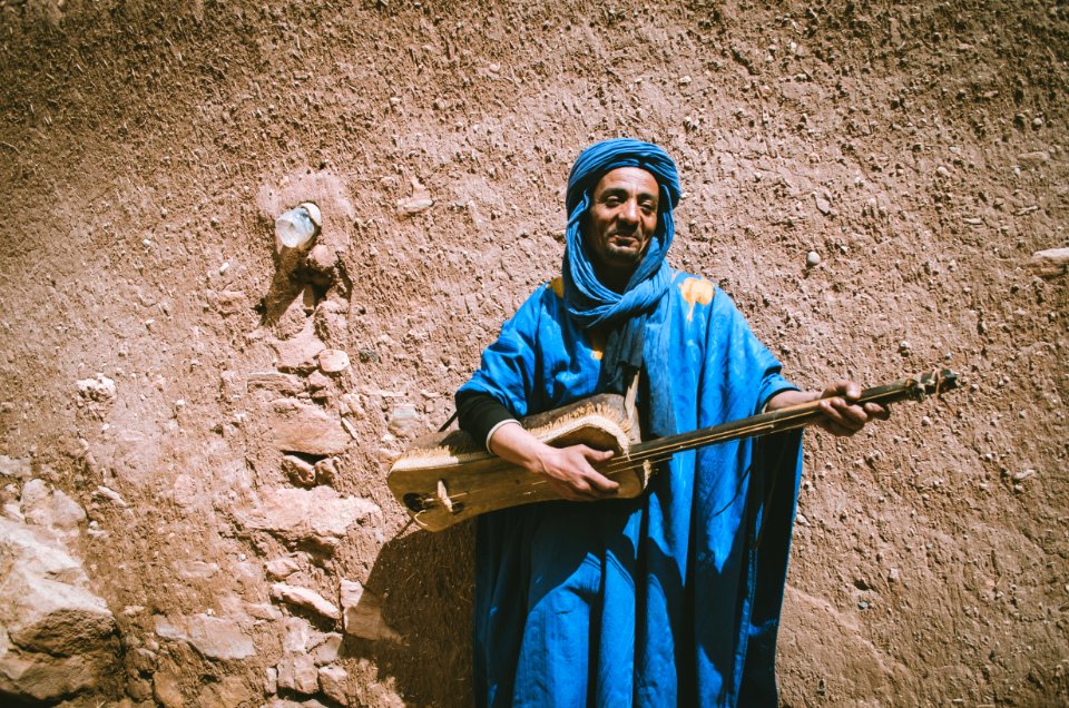 Man Wearing Blue Top Holding Brown String Instrument