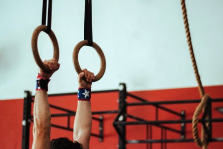 Male Gymnast Holding On To Two Wooden Rings