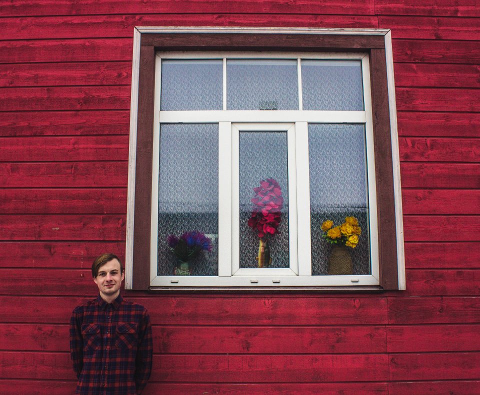 Man In Red And Black Dress Shirt Standing Beside A Red Wall