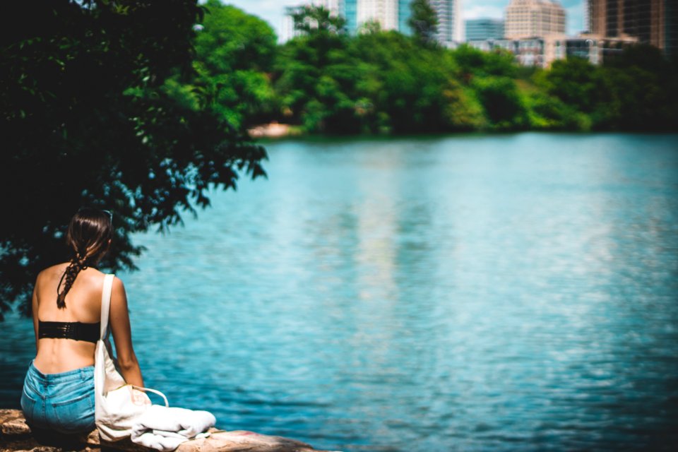 Woman In Black Top Sitting Beside Body Of Water